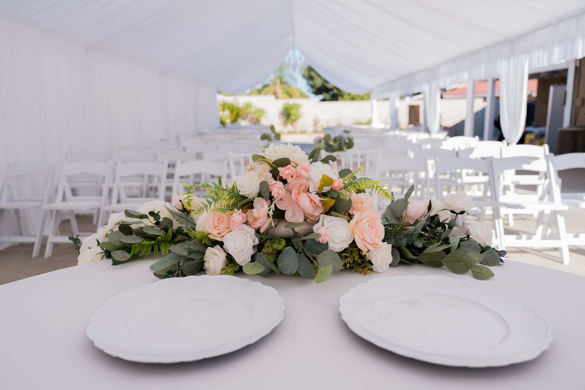 Beautifully decorated wedding reception with pink and white floral centerpiece and elegant table setting.