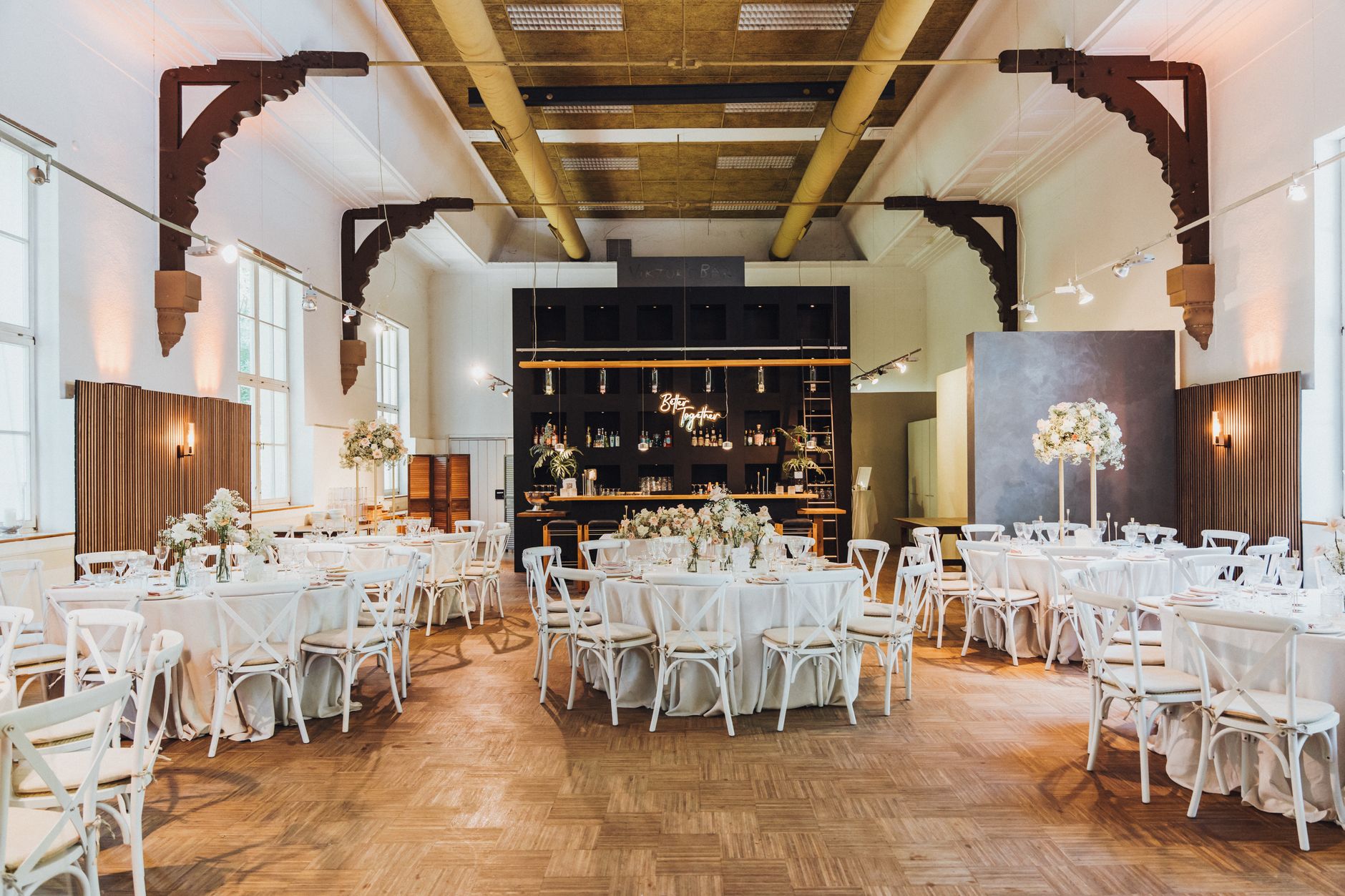 A beautifully decorated indoor wedding reception with floral arrangements and white decor.