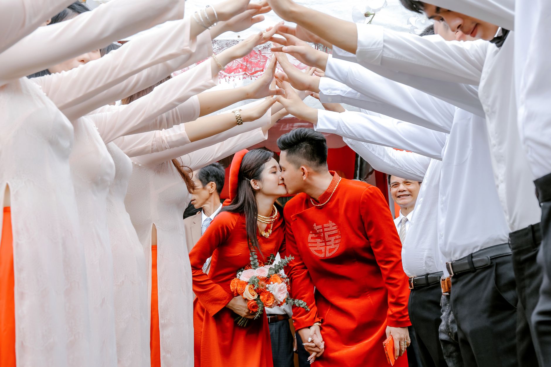 Young Asian newlyweds in wedding clothes kissing each other while standing on traditional ceremony