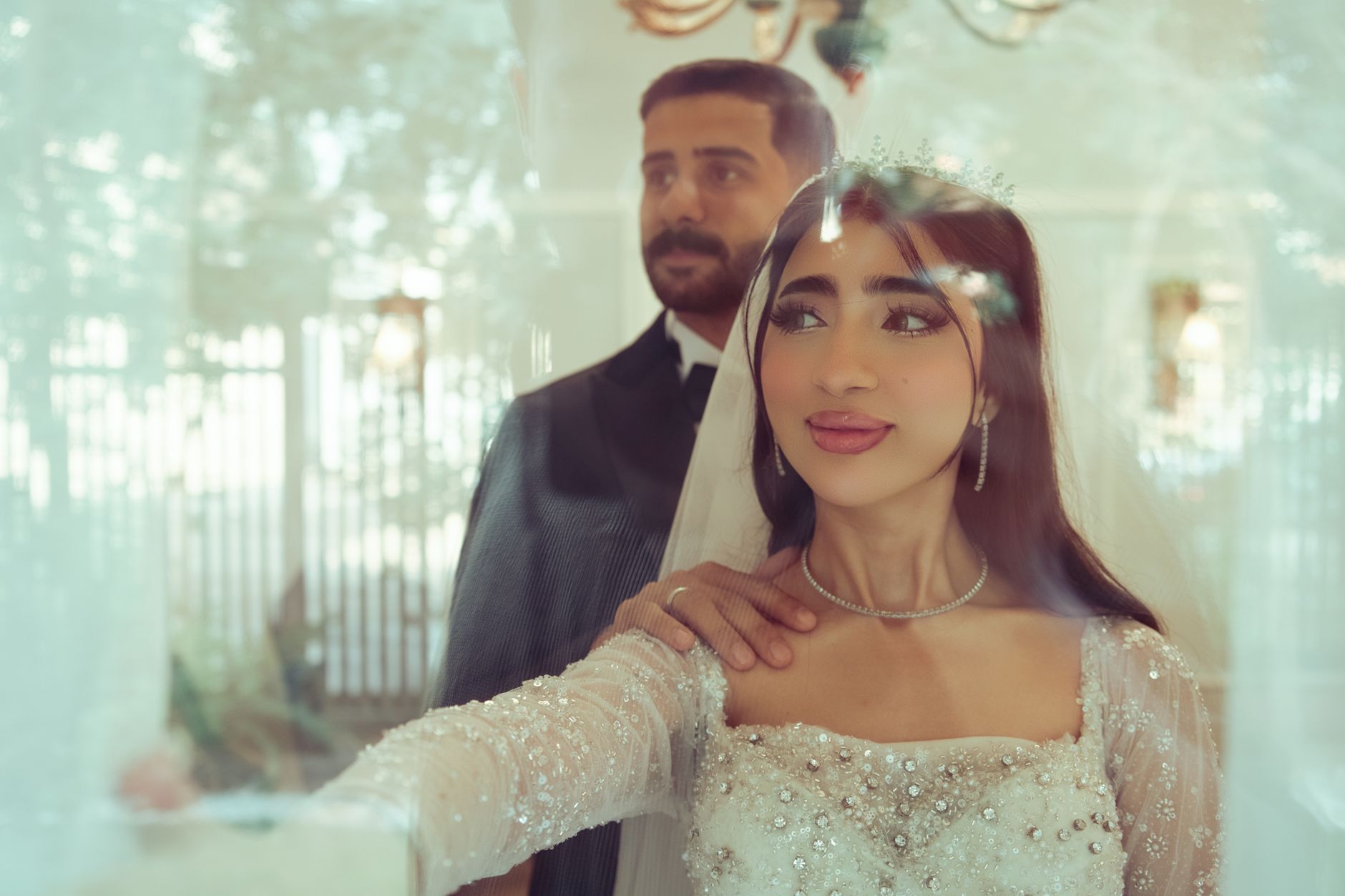 A beautiful Middle Eastern couple posing on their wedding day with a soft, dreamy atmosphere.